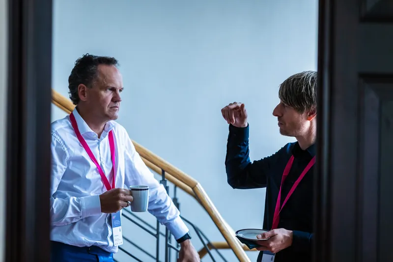 Lars Neumann and Dr. Johannes Bohnet in conversation during a coffee break on the staircase